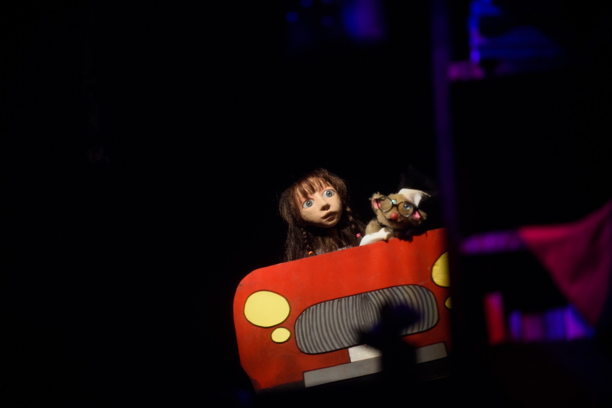 A puppet girl sits in a red car