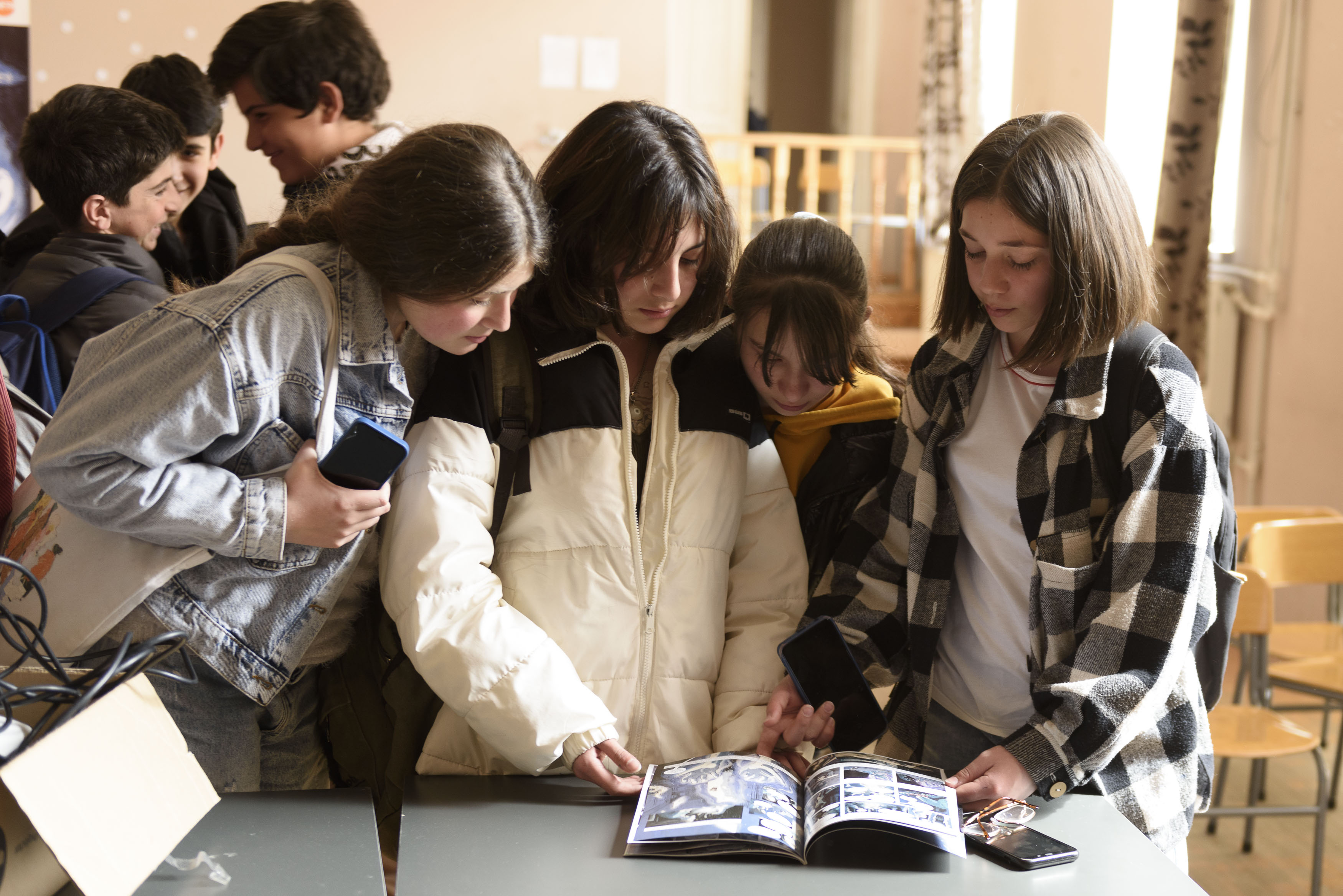 Three adolescent girls standing together, reading a comic book named Invisible
