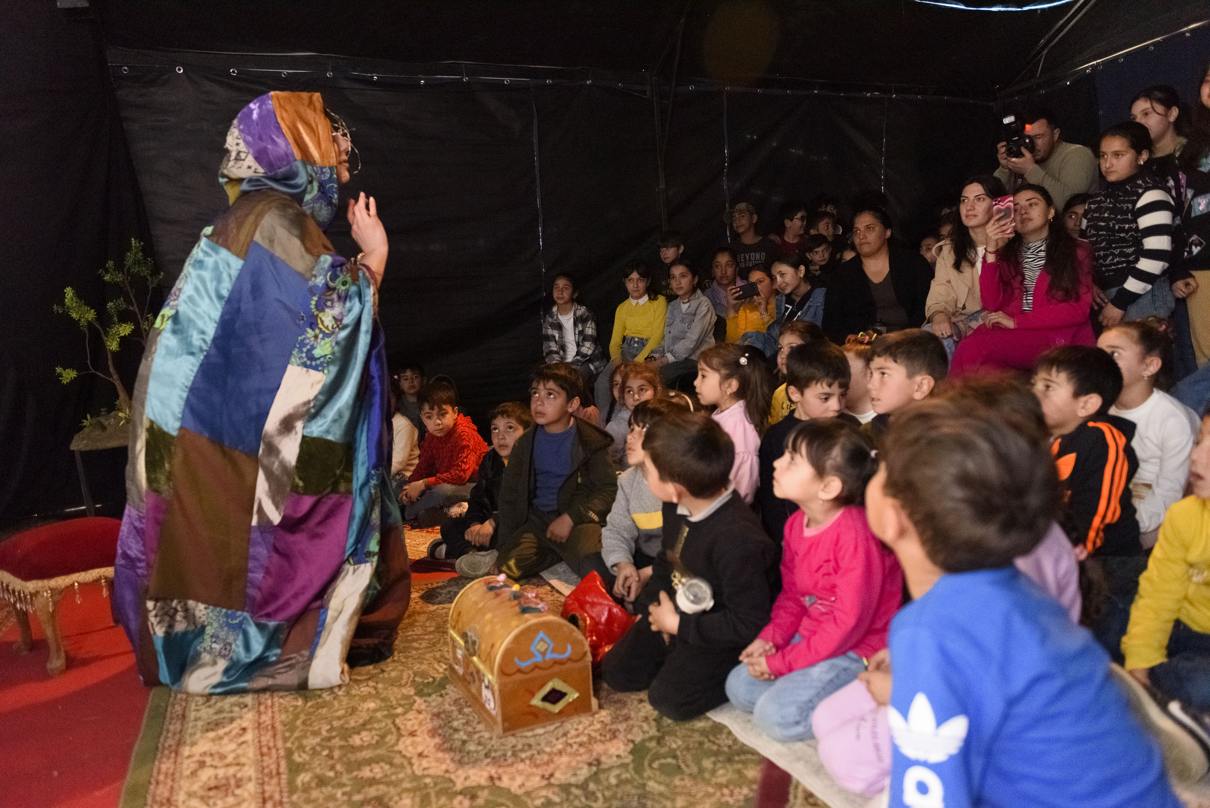 Children sitting on the carpet, watching a puppet show