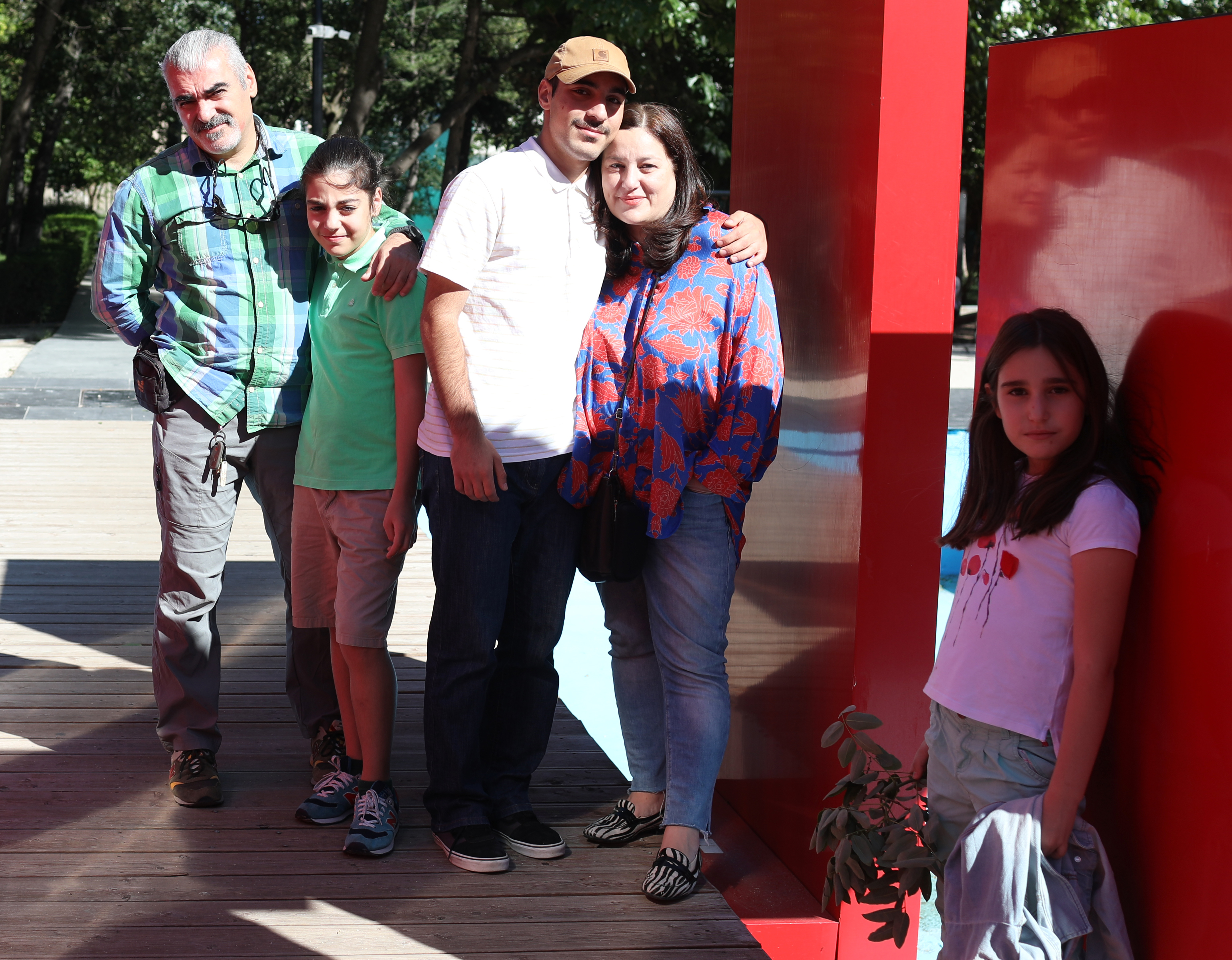 A mother, father and their three children are standing at red blocks outdoors