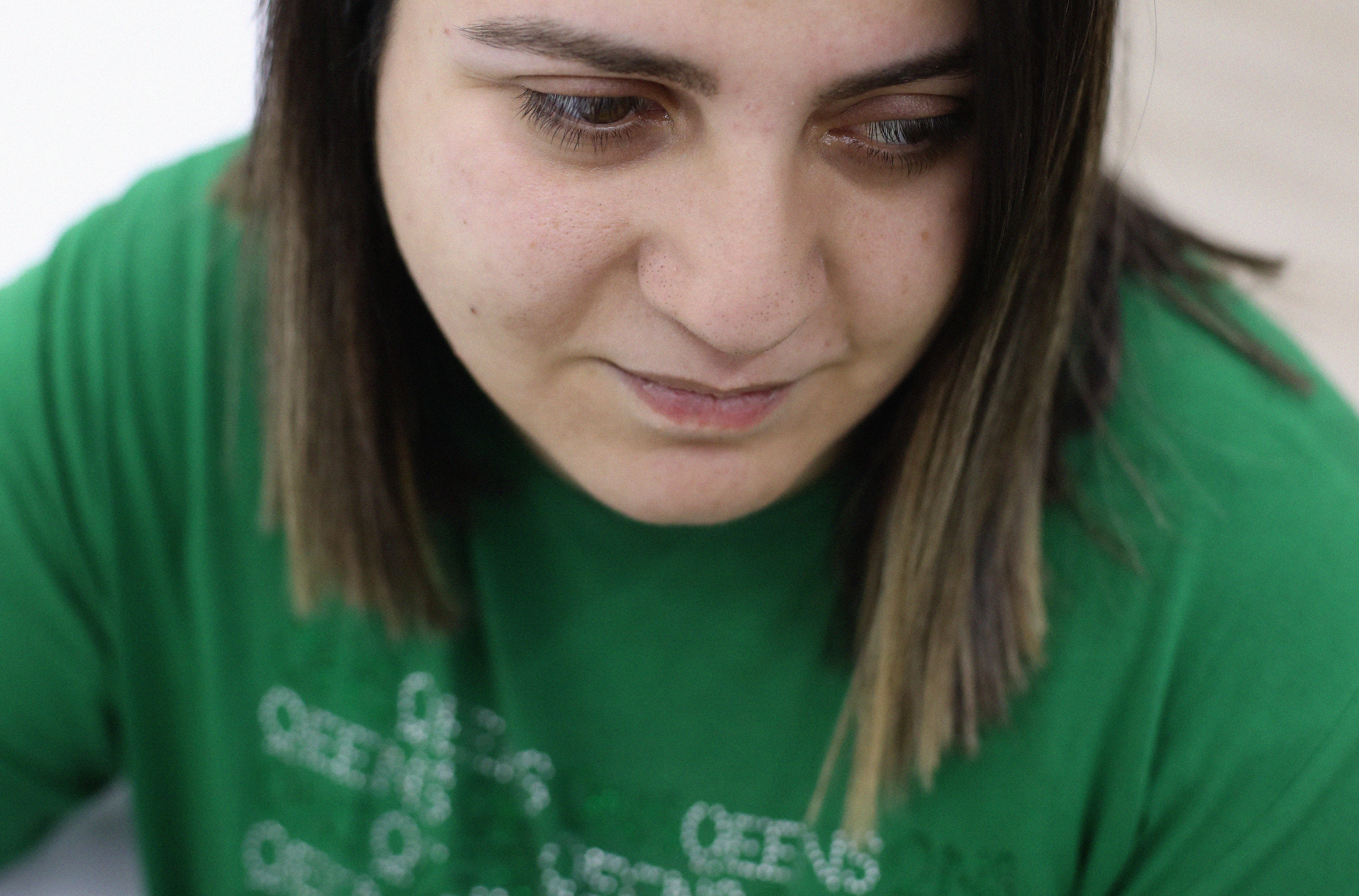 A close up of a woman, named Dea Eremashvili, wearing green suit with white texts
