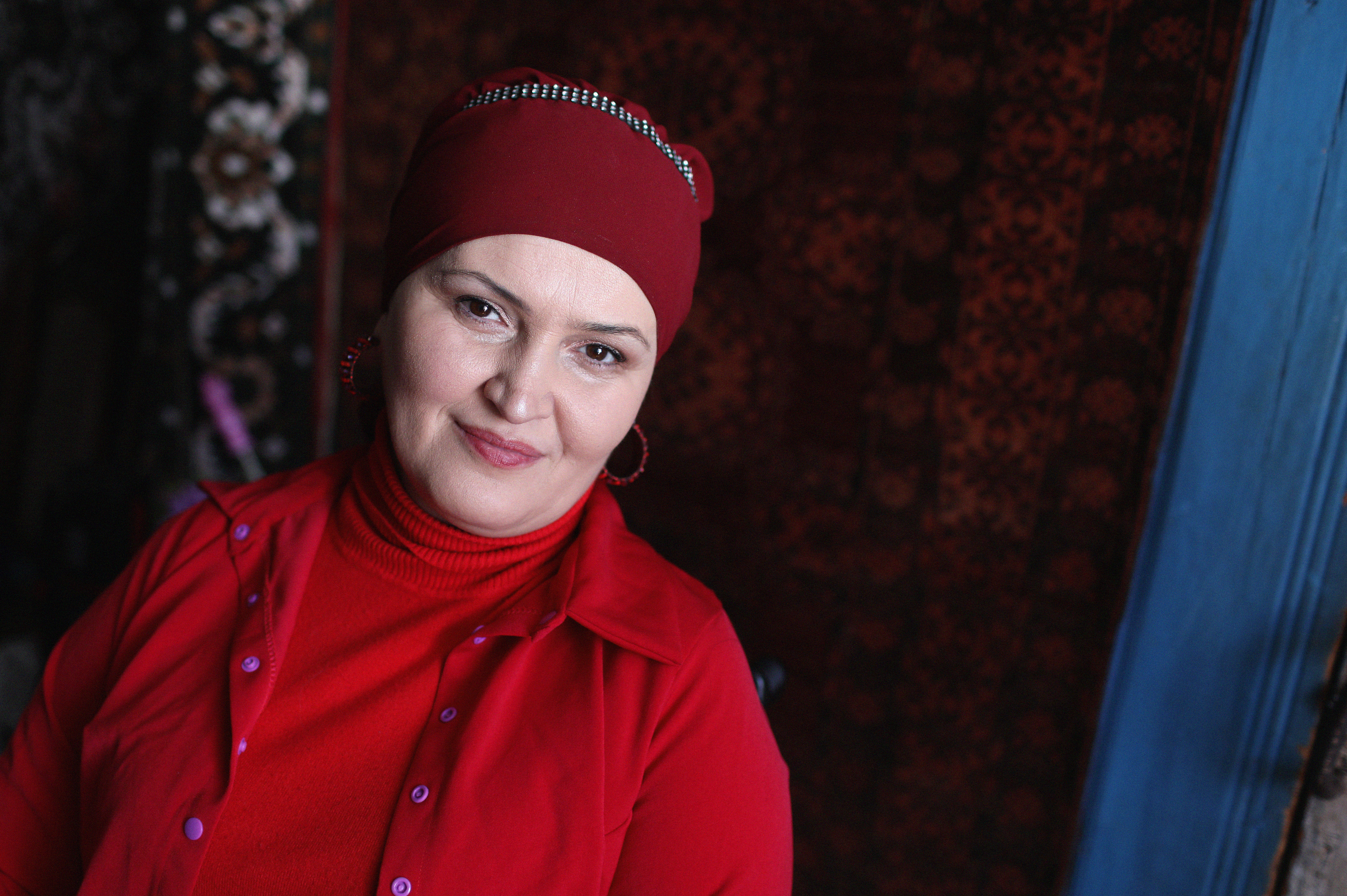 A woman, named Mzevinar Iremadze is wearing red closes and a red scarf on her head. 