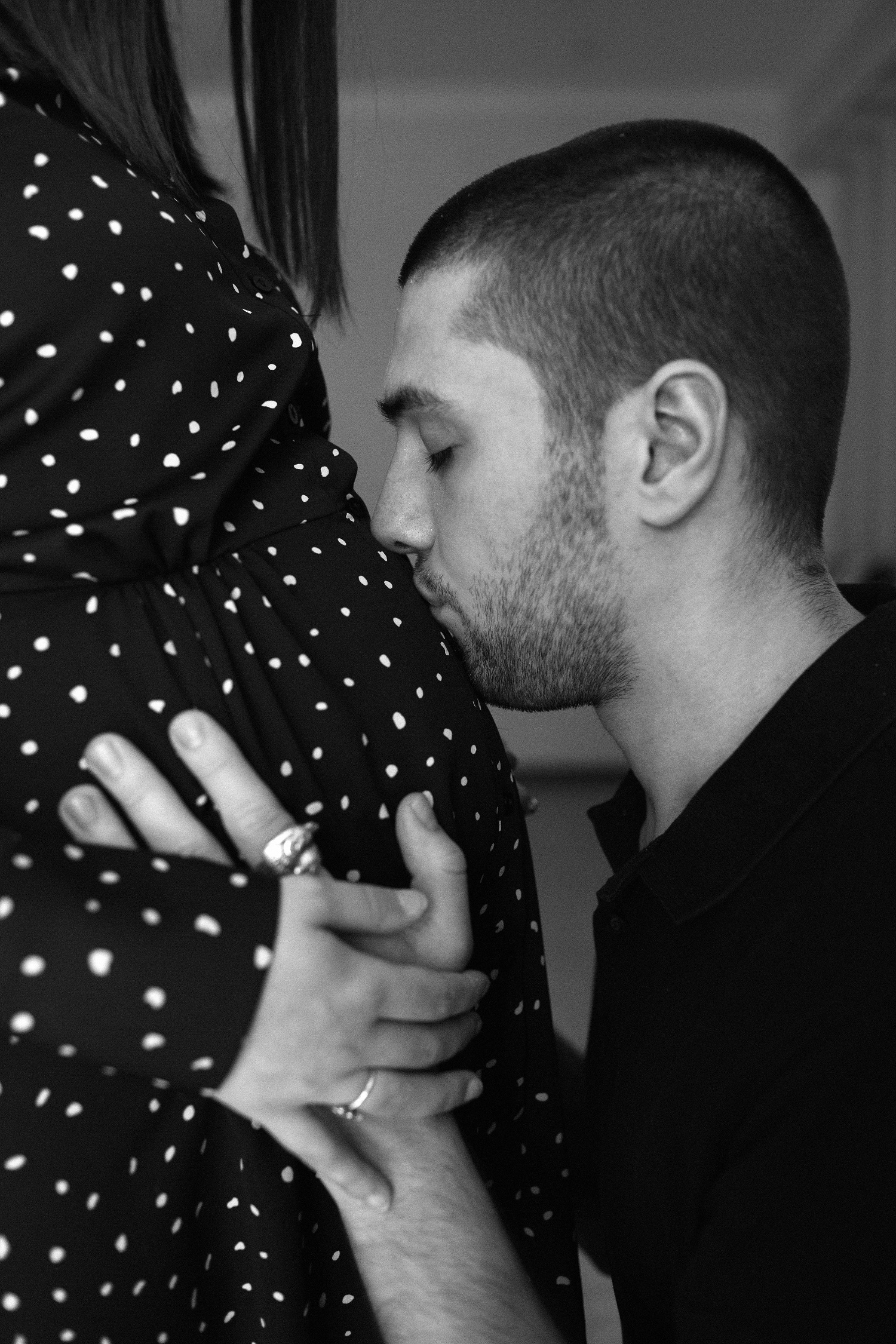 The man is kissing the belly of a woman expecting a baby