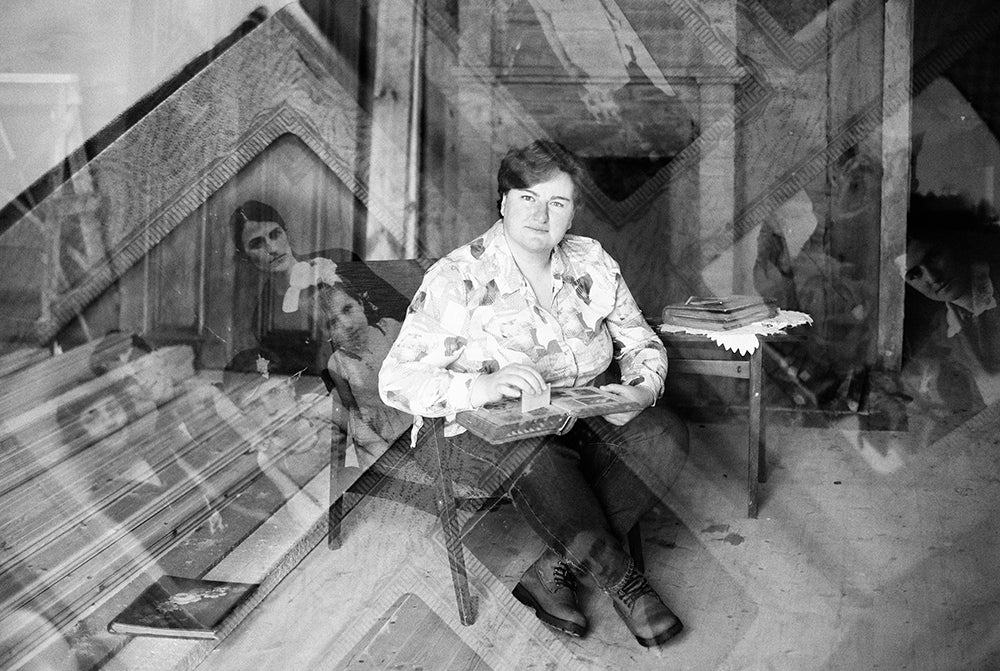 A young woman sitting on a chair. There are old photos scattered around her