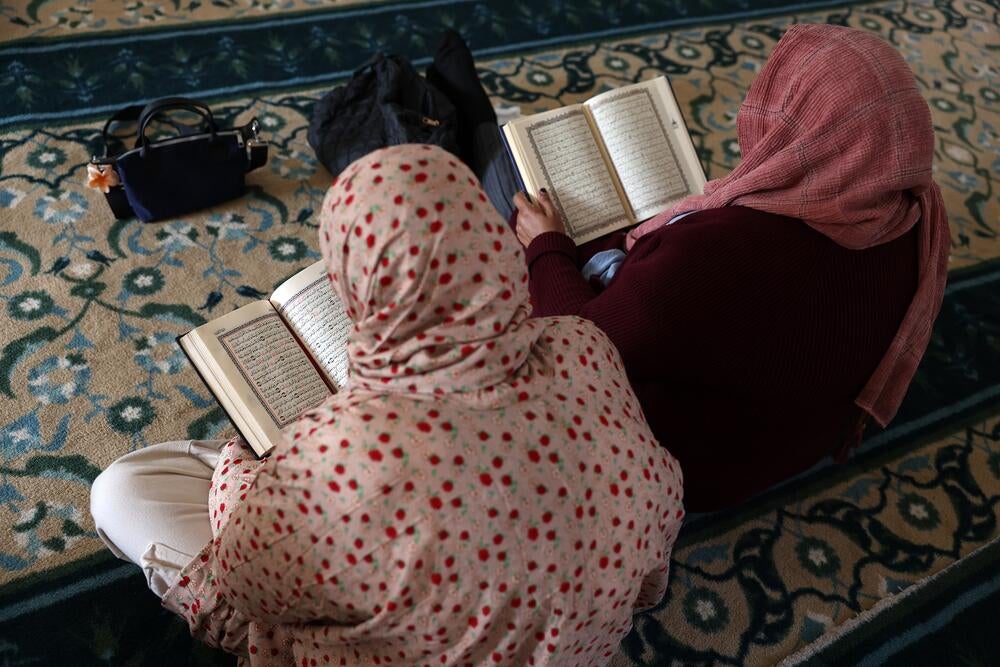 A Muslim woman sitting on a floor reading a book