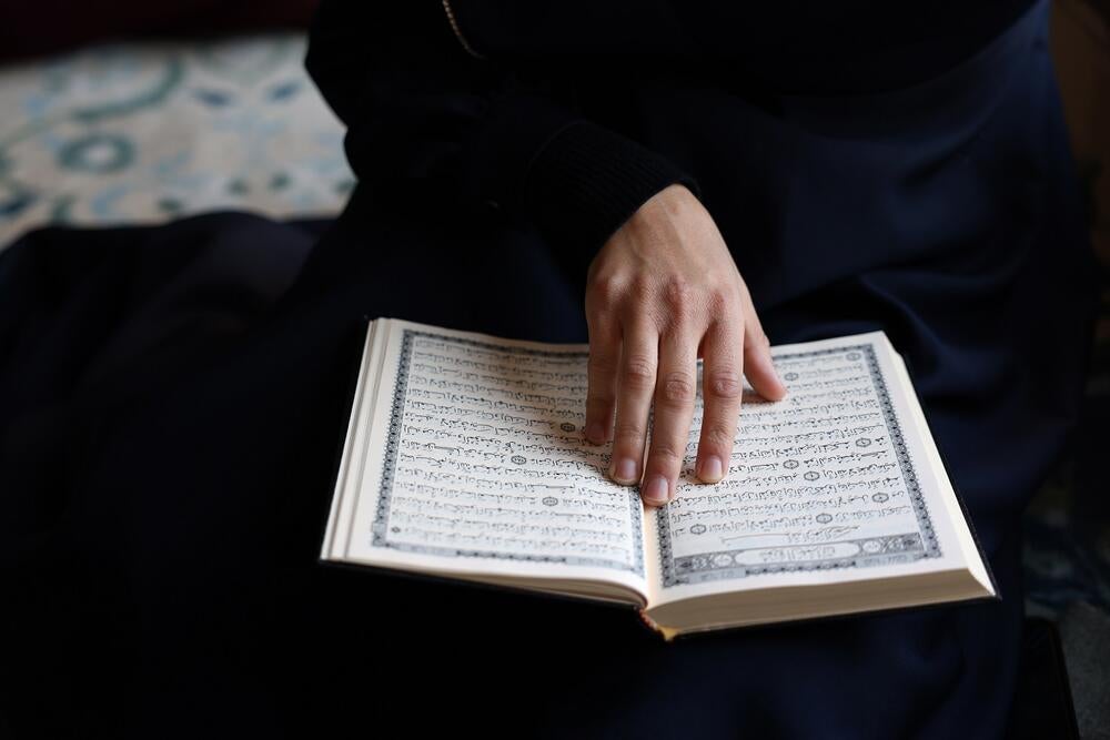 A close up to a book and a hand of allegedly a Muslim woman