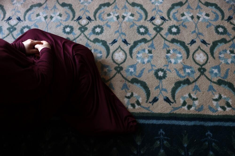 A close up to hands and part of body of a Muslim woman sitting on the floor