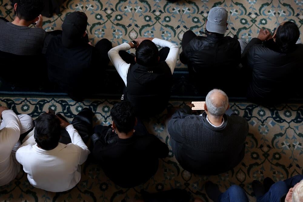 A bunch of Muslim men sitting on the floor of a Mosque