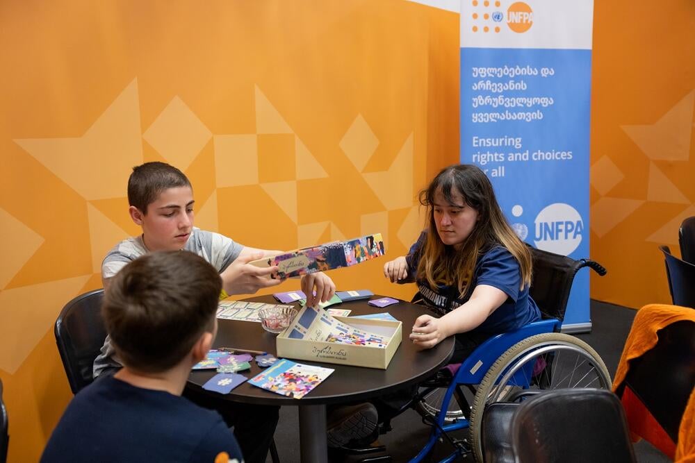 Young people playing a board game. One of the girls is on a wheelchair