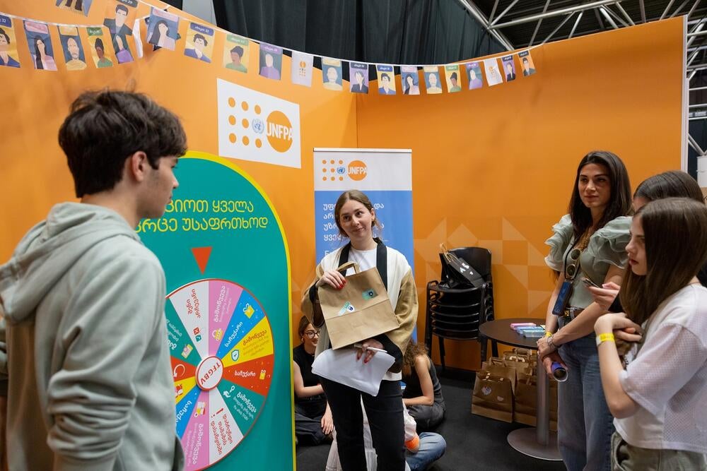 A number of people standing at a wheel of fortune, playing a game