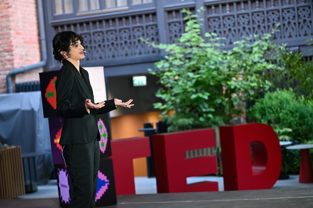 A young woman named Lizi Katamadze, who is wearing black suit, is standing on a stage 