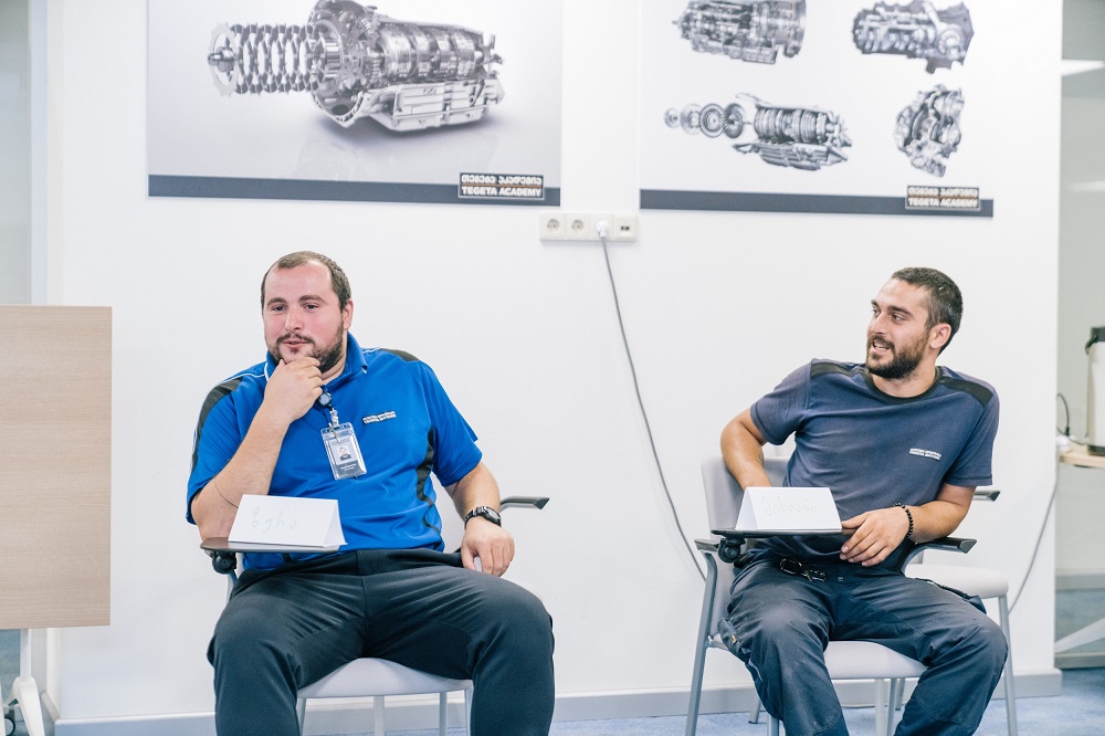 Two men sitting on chairs, talking and smiling