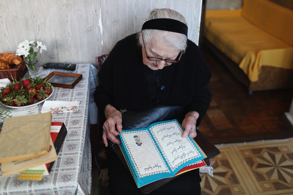 An elder women wearing black is looking into an album