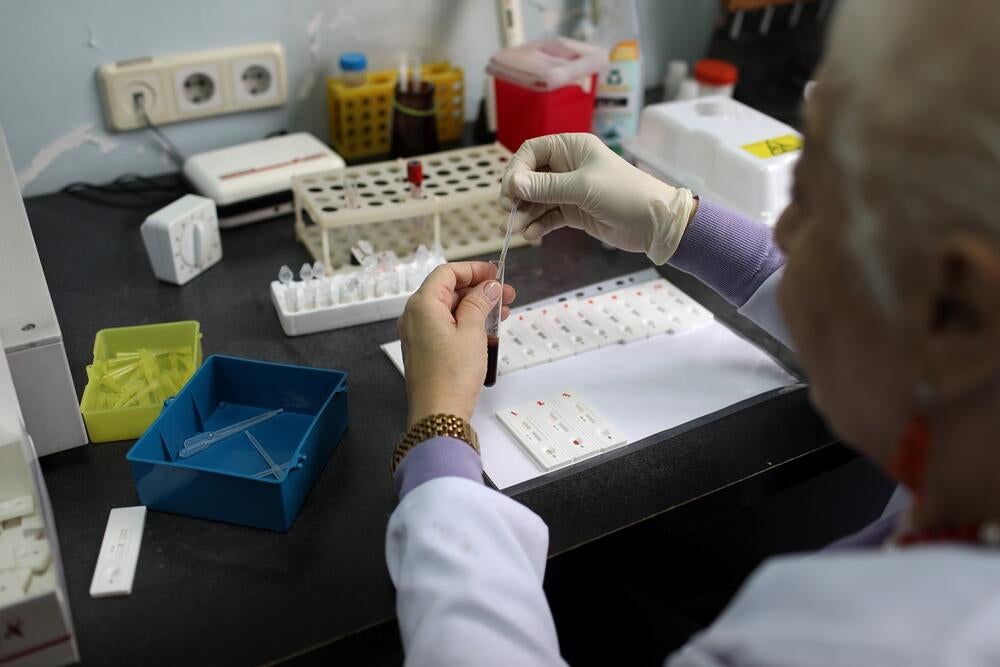 An elder woman in white suit is making HIV testing 