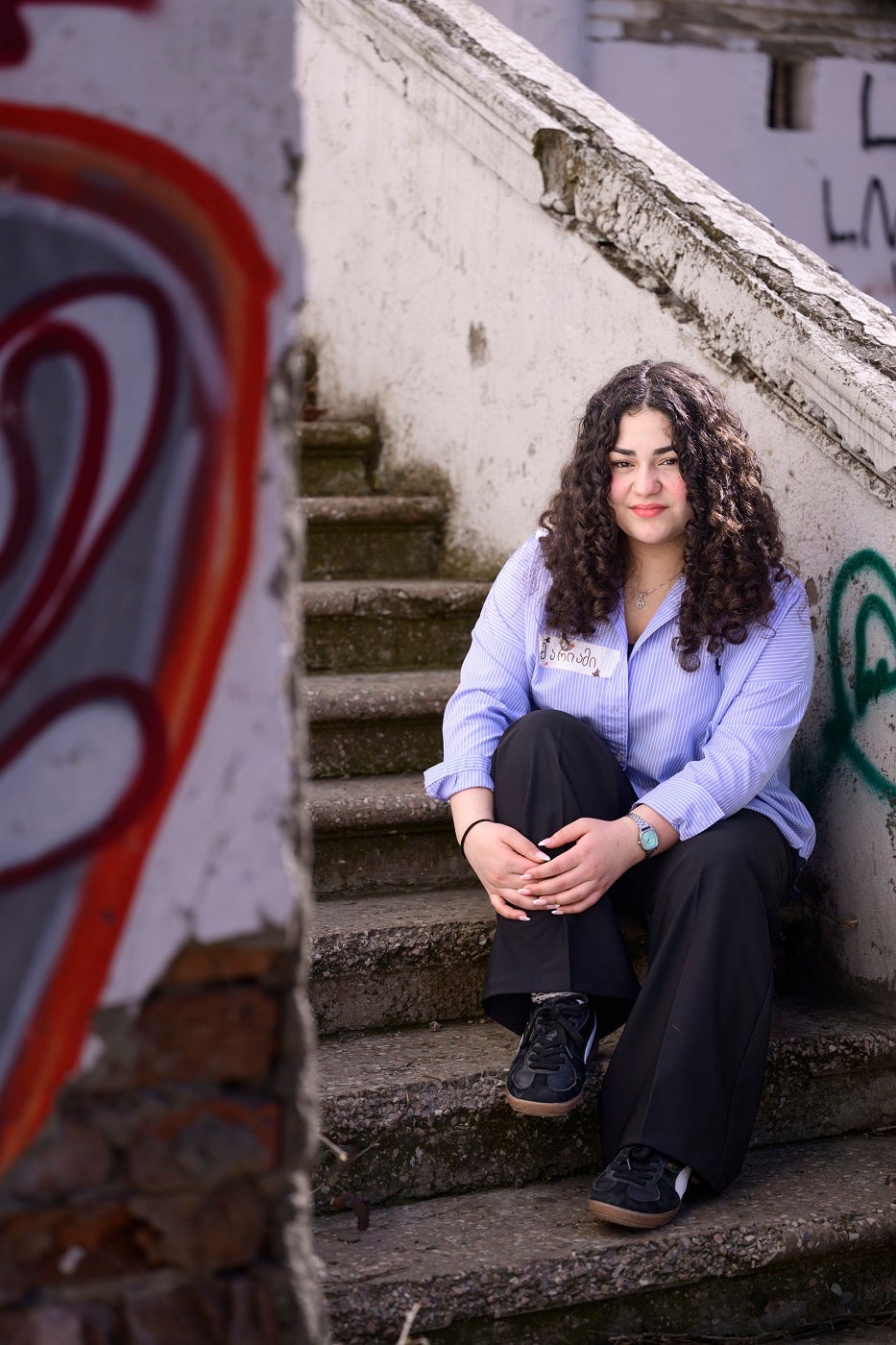 A curly girl is sitting on the stairs