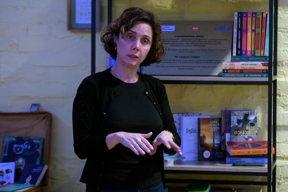Head of local civil-society organiztaion Nina Khatiskatsi standing and talking in front of a bookshelf