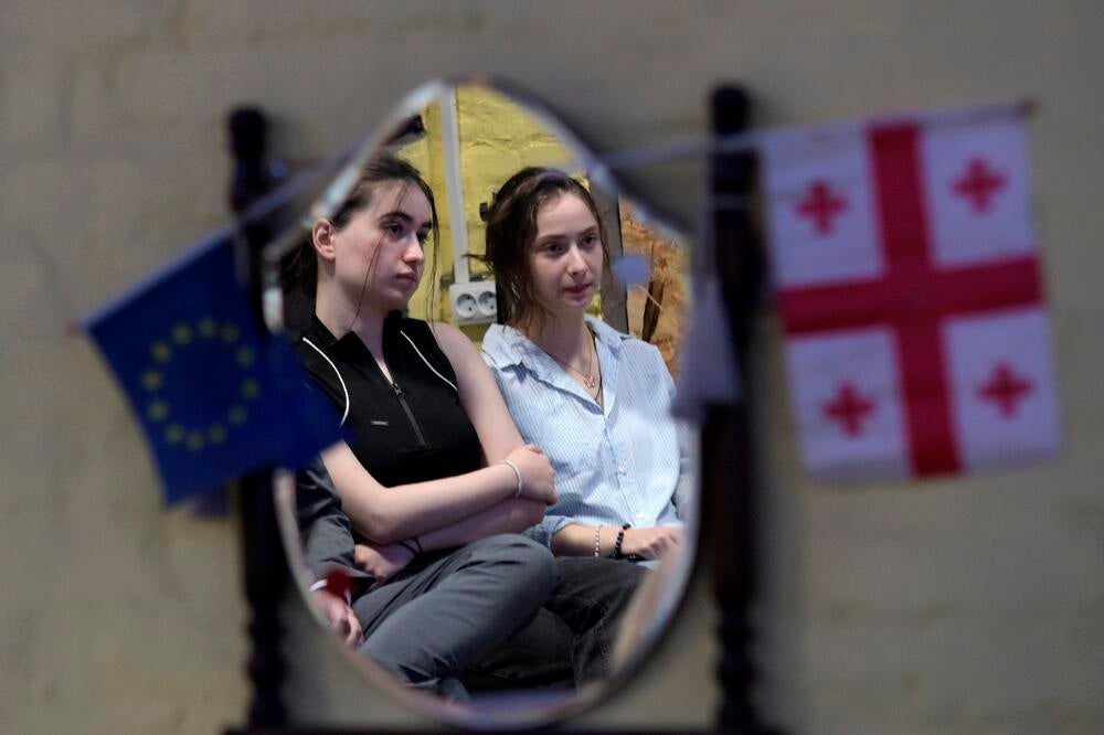 Two young women seen from the mirror which has a Georgian and European Union flags