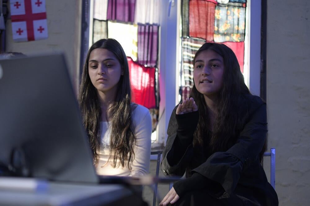 Two young women sitting together. One of them is talking
