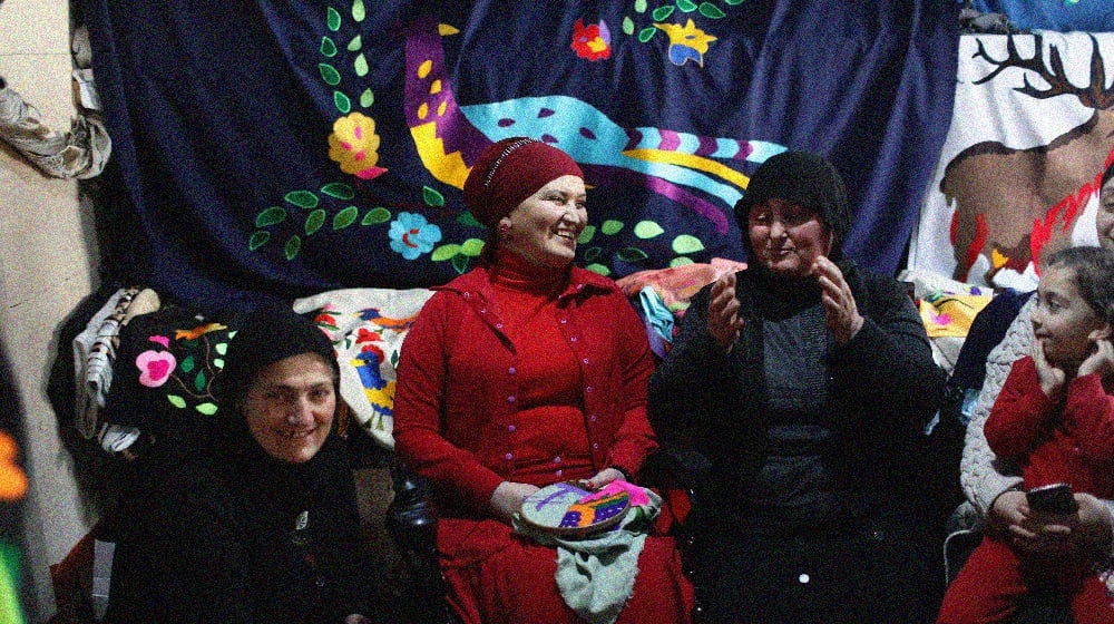 Four women and a small girl are sitting in front of traditional textiles in mountainous Adjara region of Georgia