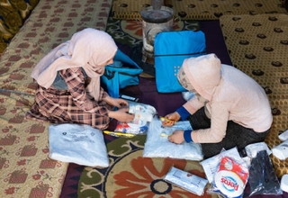 Teenagers Salwa (left) and Kholoud look through the contents of their dignity kits at the AlSekka camp in Idlib, Syria.