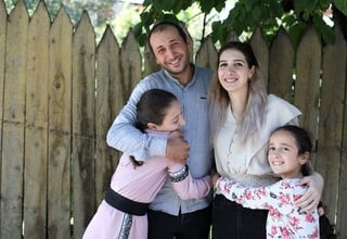 A family of a husband, wife and two daughters holding one another 