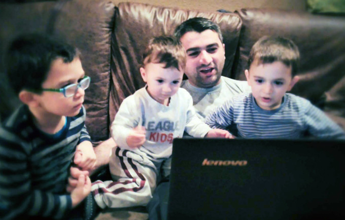 A father and his three sons watching cartoons