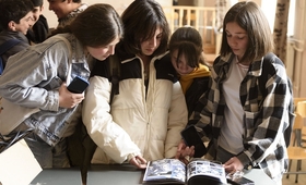 Three adolescent girls reading the comic book