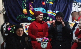 Four women and a small girl are sitting in front of traditional textiles in mountainous Adjara region of Georgia