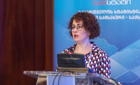 Head of UNFPA Georgia Country Office, Mariam Bandzeladze is standing at a microphone. She has short curly hair and glasses