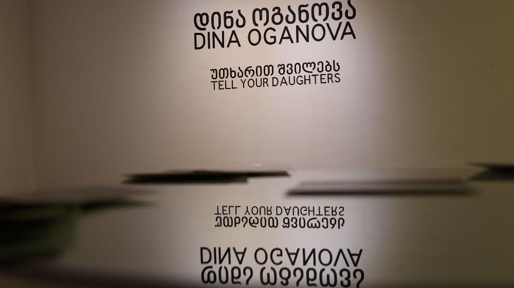 The text on the wall reads Dina Oganova, Tell Your Daughters - the name of the artist and the title of her exhibition