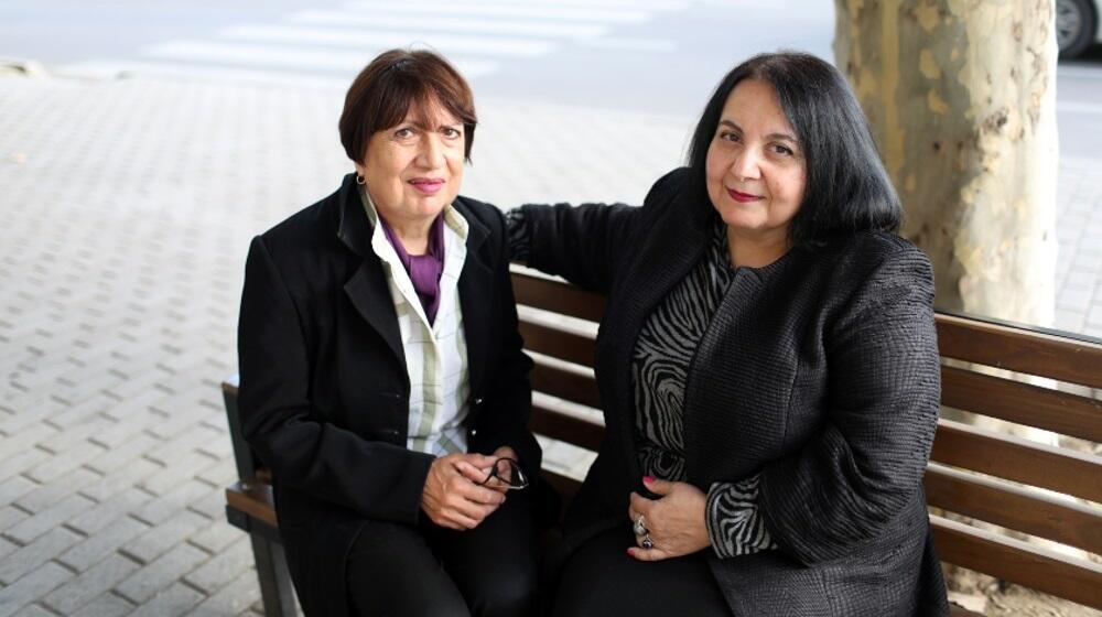 Two women sitting on a bench outdoors