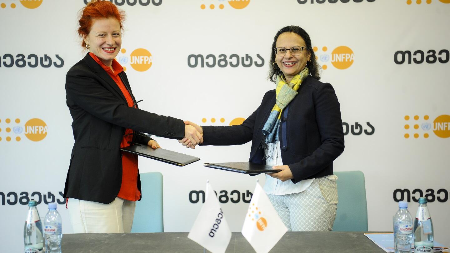 Two female heads of Tegeta Holding and UNFPA shake hands, smiling 