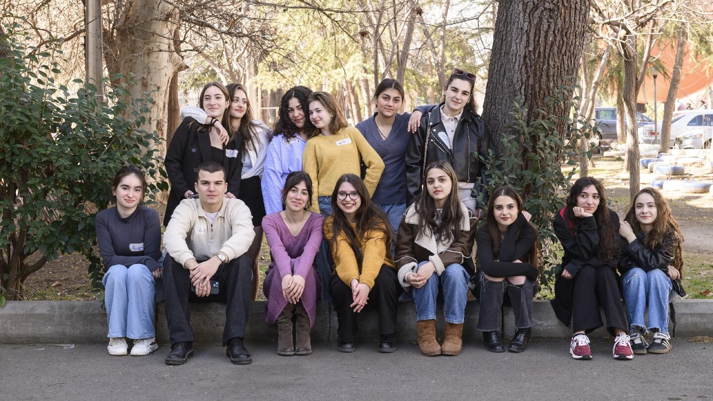 13 girls and 1 boy gathered outdoors in nature ready for the photoshoot