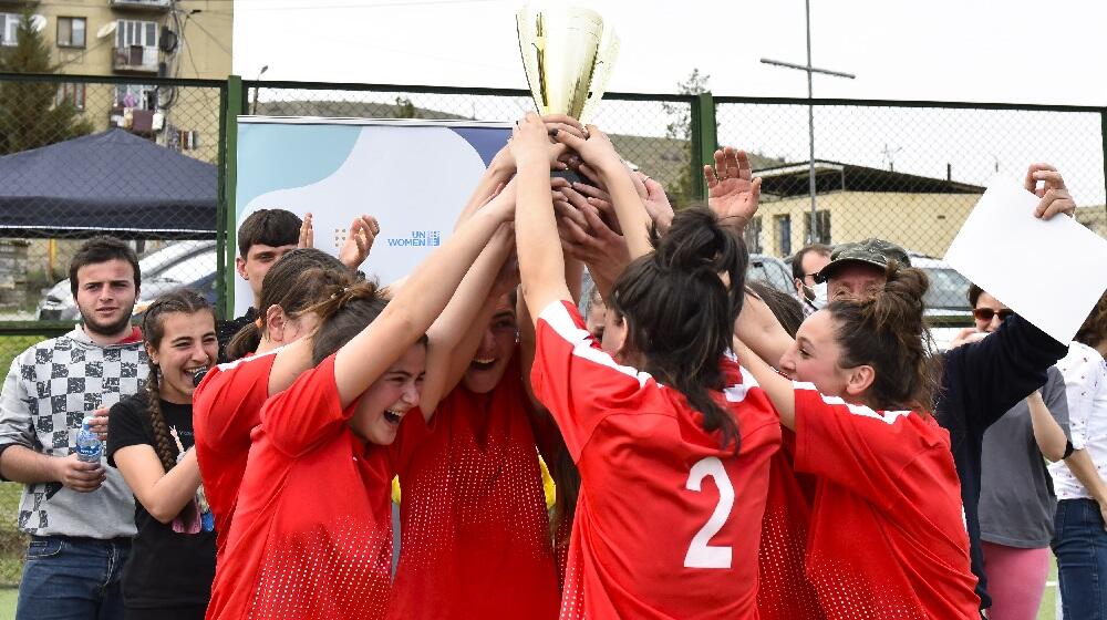 გამარჯვებული გუნდის წევრი გოგოები თასს ერთად წევენ ჰაერში