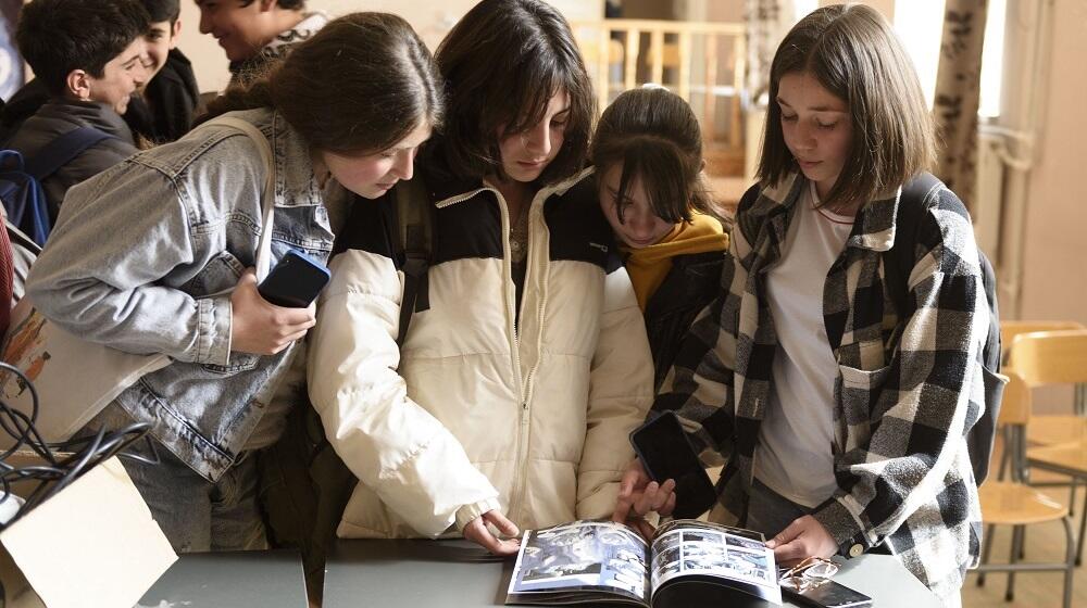 Three adolescent girls reading the comic book