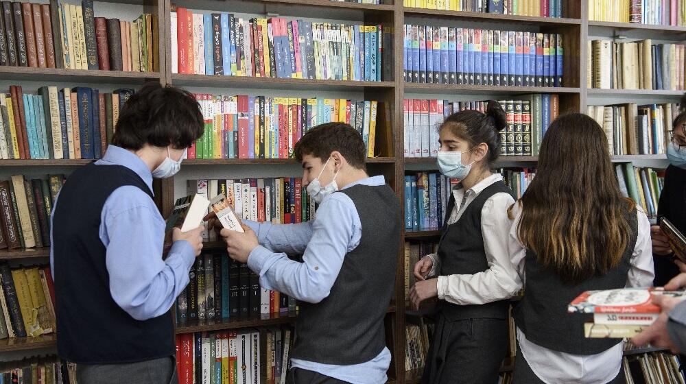 Girls and boys looking at the books on the shelves