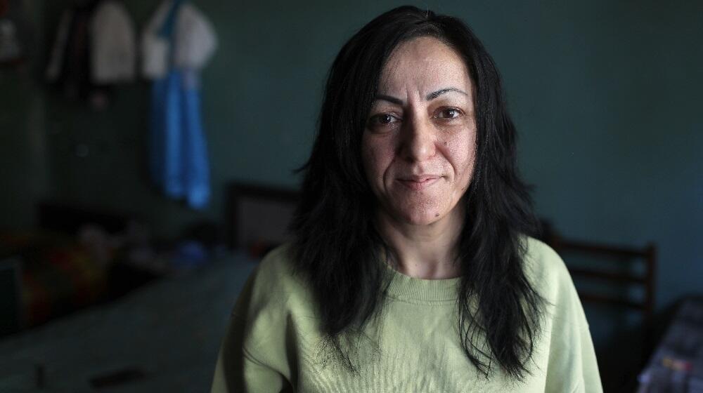 A woman with long black hair and green sweater