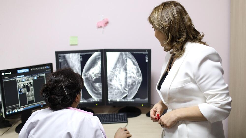 Two woman in medical coats are looking at a computer screen 