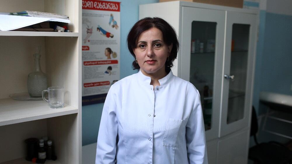 A woman wearing doctor's suit is standing in the middle of a room