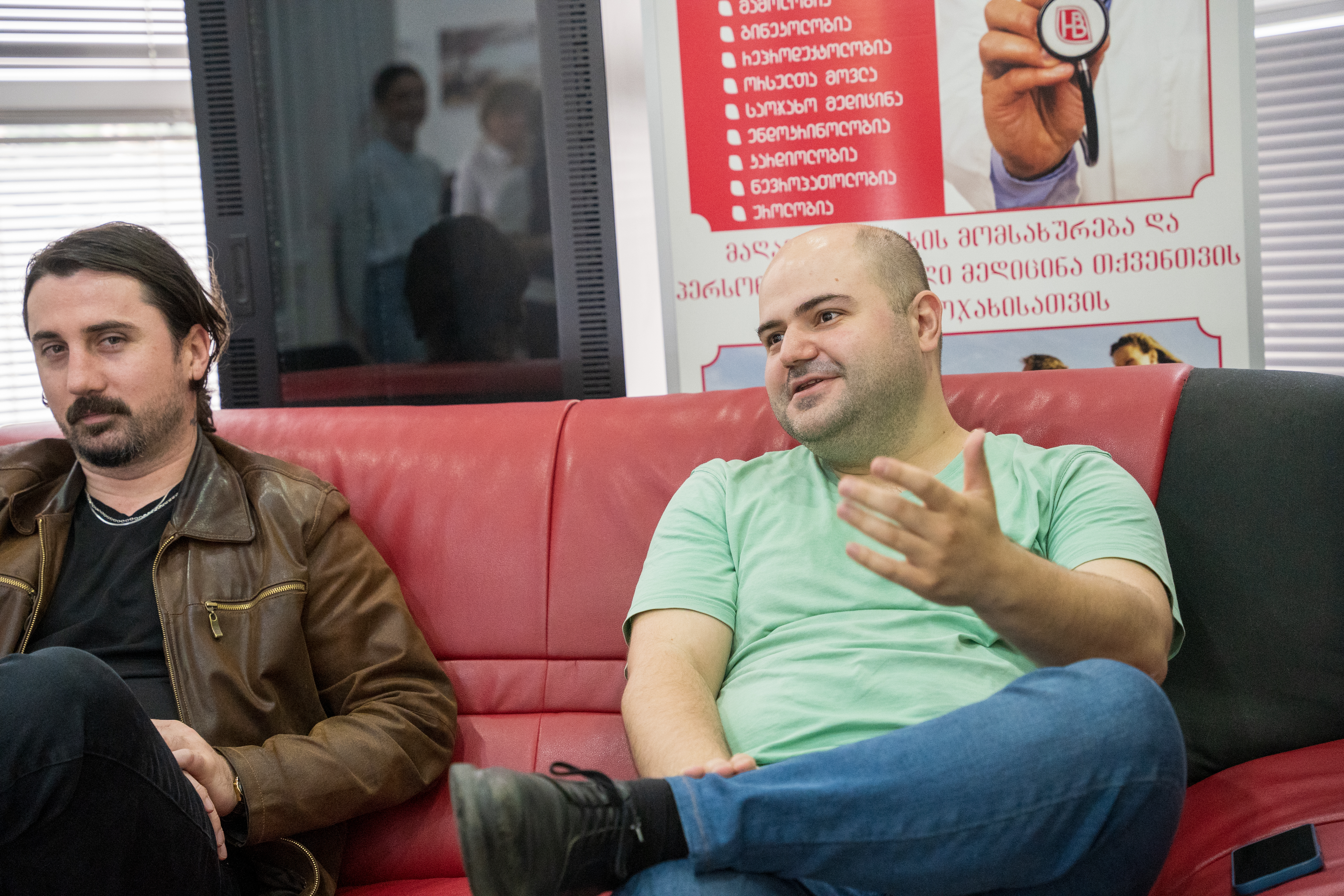 Two men sitting on the chair, talking